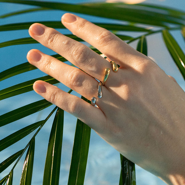 Ohui Ring von PURELEI in Gold mit tropfenförmigem Design, getragen vor tropischem Palmenblatt, elegant und wasserfest.