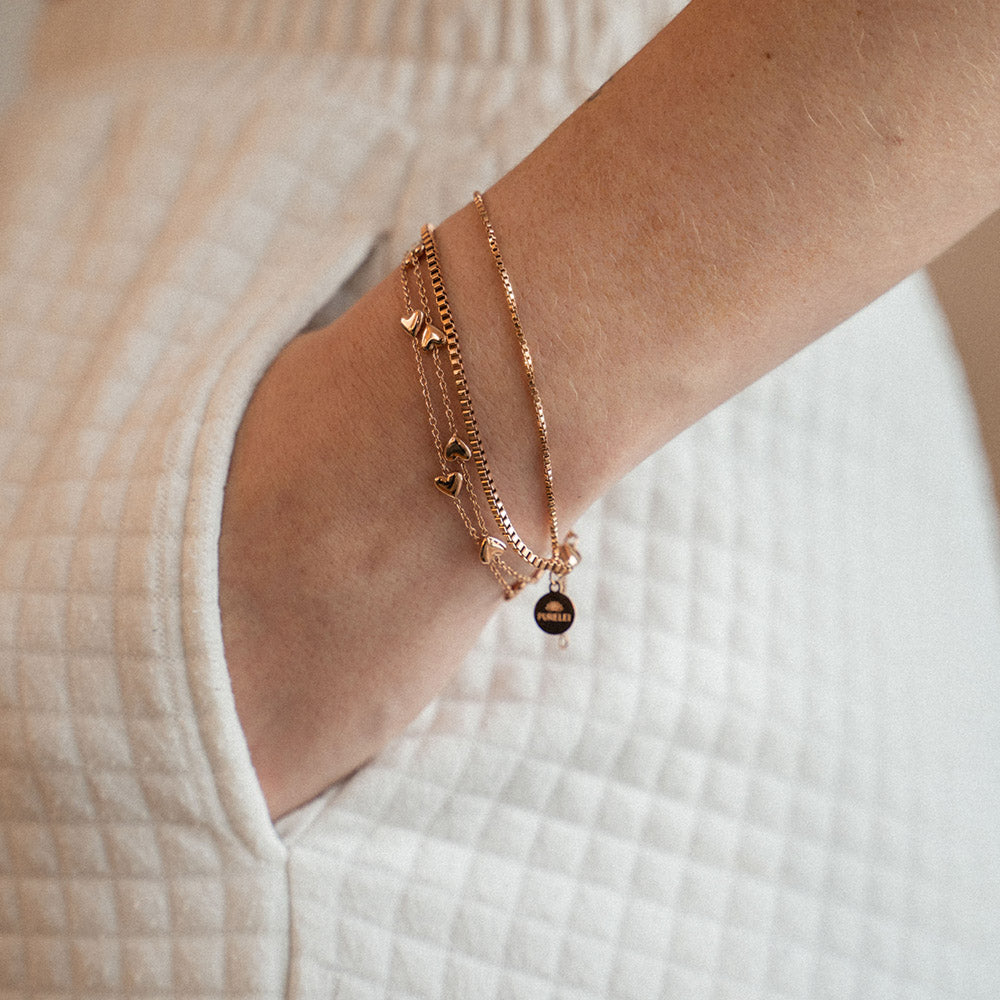 Das Alohi Heart Armband in Roségold mit filigranen Herzen am Handgelenk, elegant und nickelfrei von PURELEI.