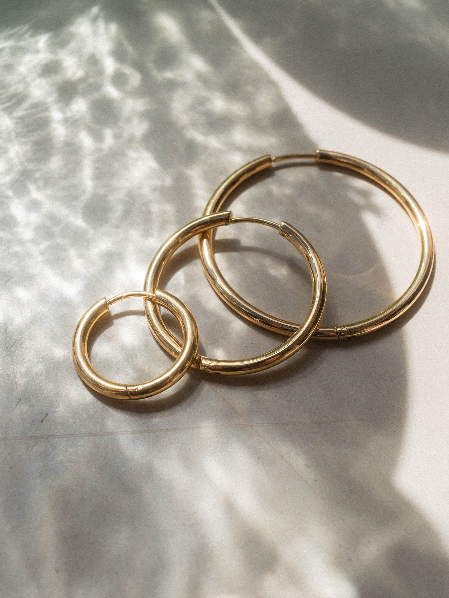 Drei silberne Creolen von PURELEI in verschiedenen Größen, elegant auf hellem Untergrund.