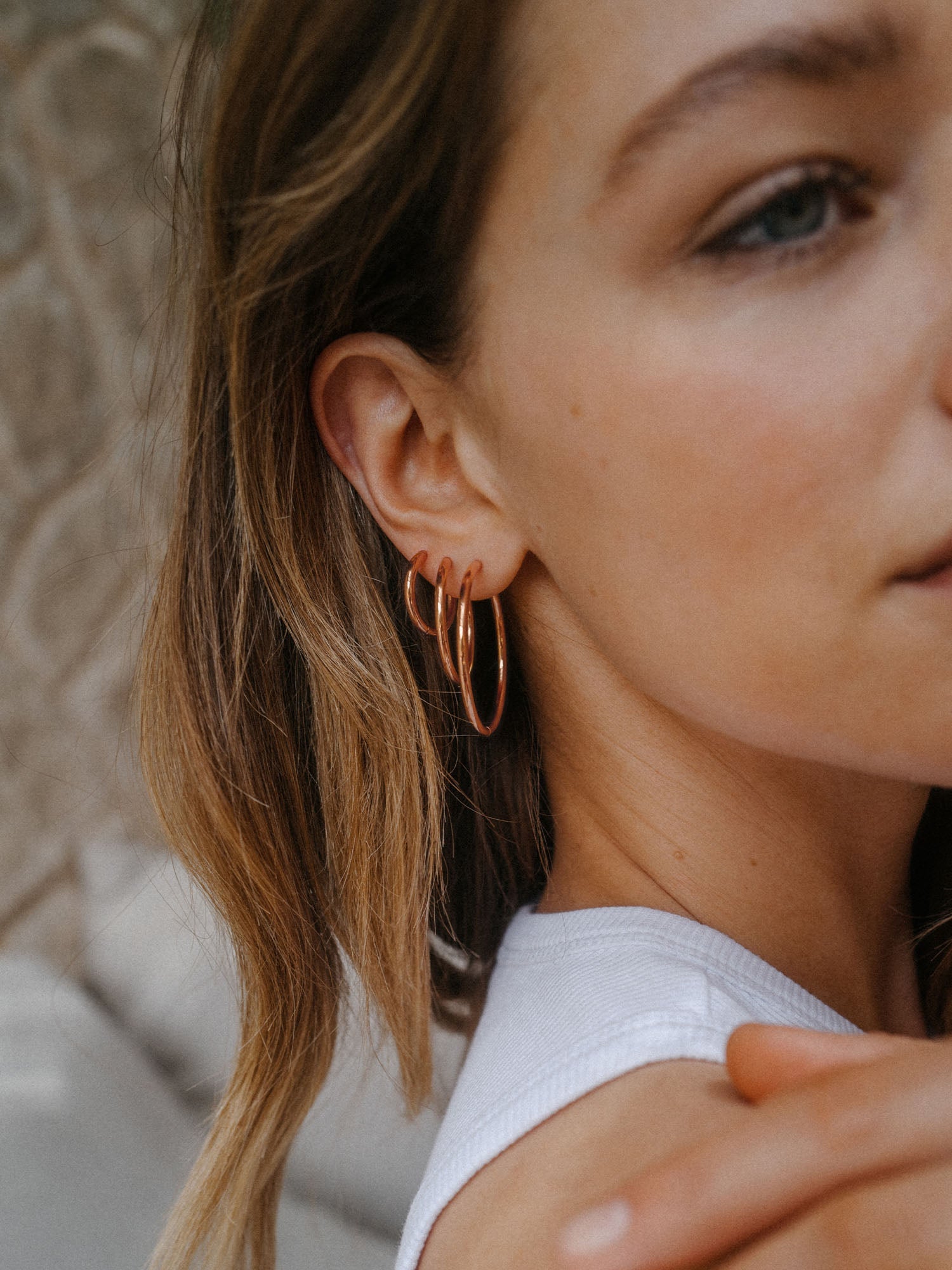 Roségoldene Creolen von PURELEI, elegant und modern, getragen am Ohr einer Frau.
