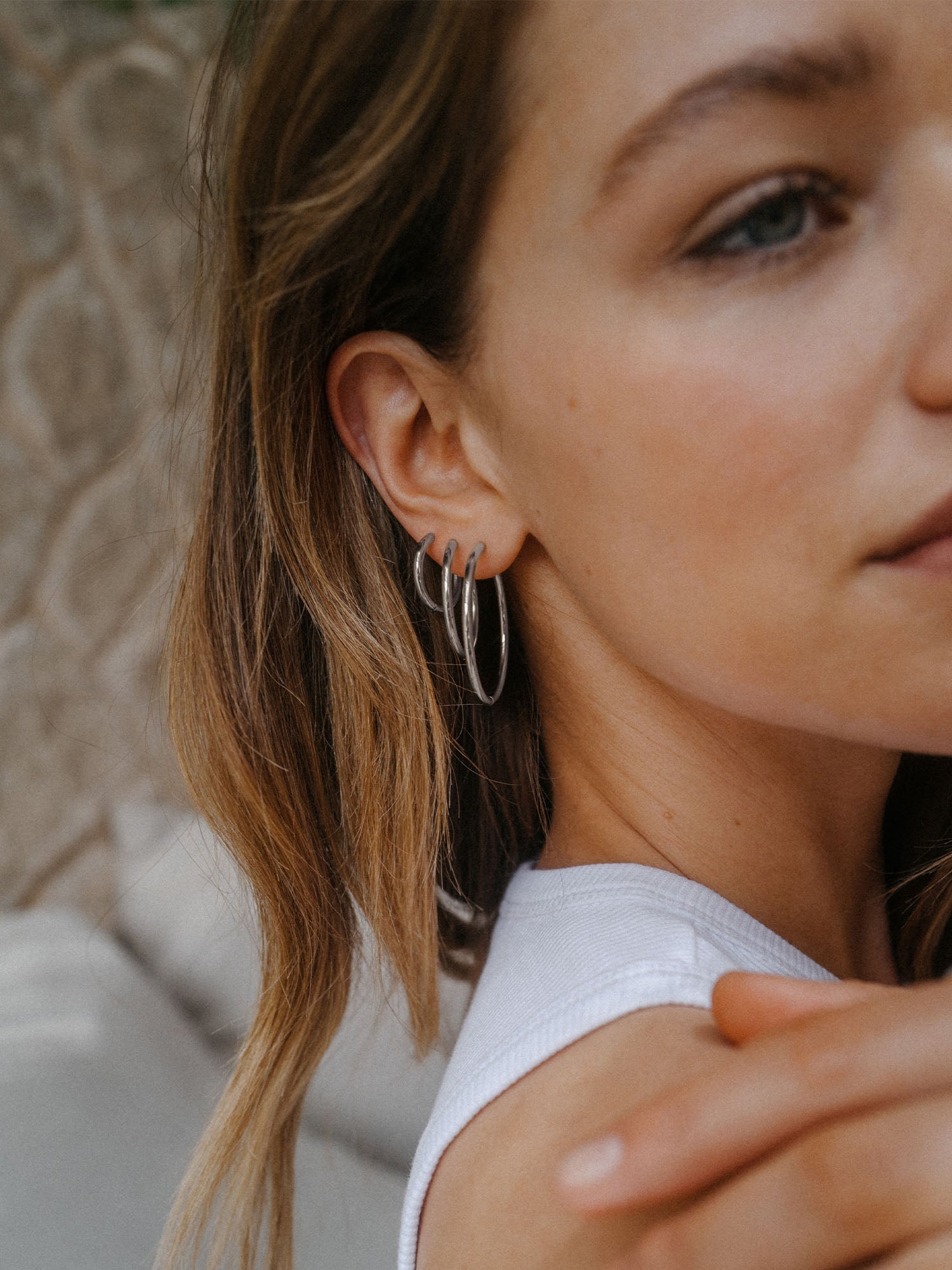 Silberne Creolen von PURELEI, elegant und modern, getragen im natürlichen Licht.