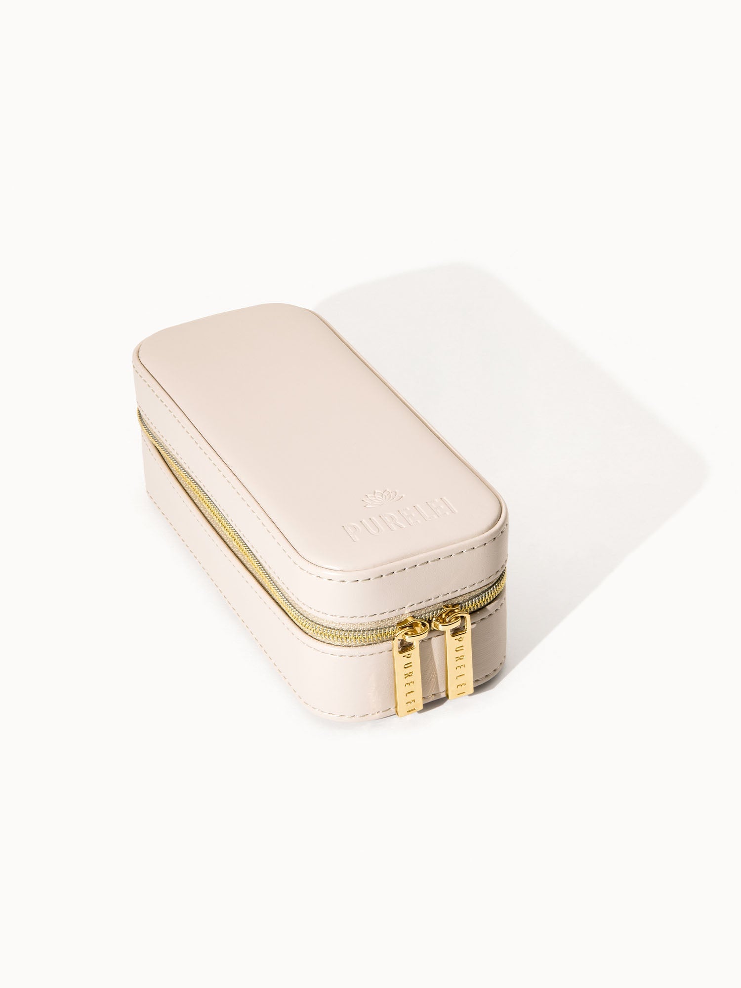 Elegante, cremefarbene Schmuckbox von PURELEI mit goldenen Reißverschlüssen.