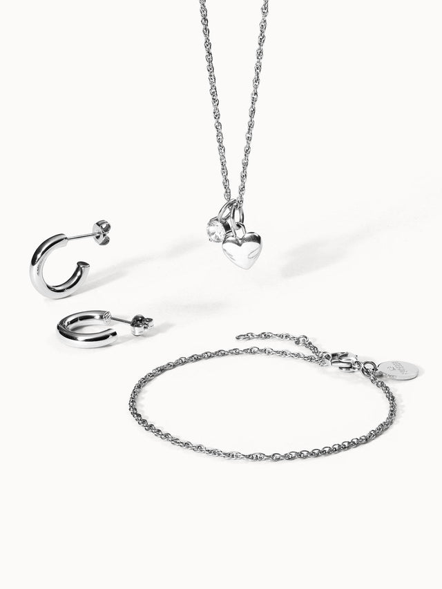 Silberne Schmuckstücke von PURELEI: Herzanhänger, Creolen und Armband, elegant und modern.