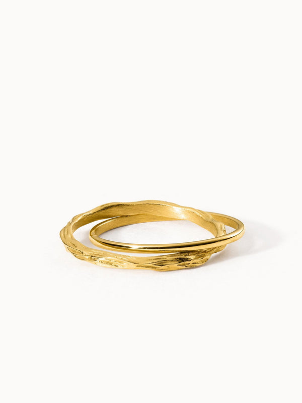 Zwei goldene Ringe mit wellenförmigem Design von PURELEI, elegant und modern.