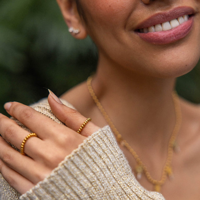 Roségoldene Ringe und Kette, elegant getragen mit warmem Strickpullover – PURELEI.