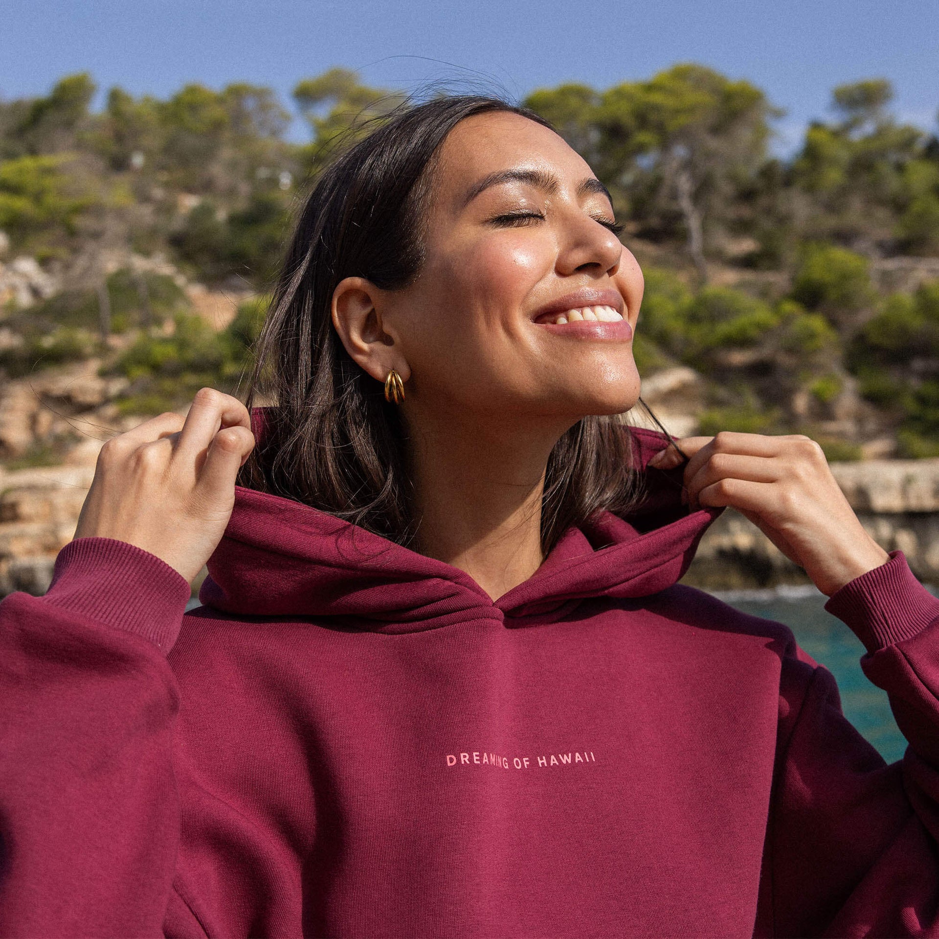 Locker sitzender weinroter Baumwollmix-Hoodie von PURELEI mit Kapuze und Hawaii-inspiriertem Schriftzug, strahlt Sommerfreude aus.