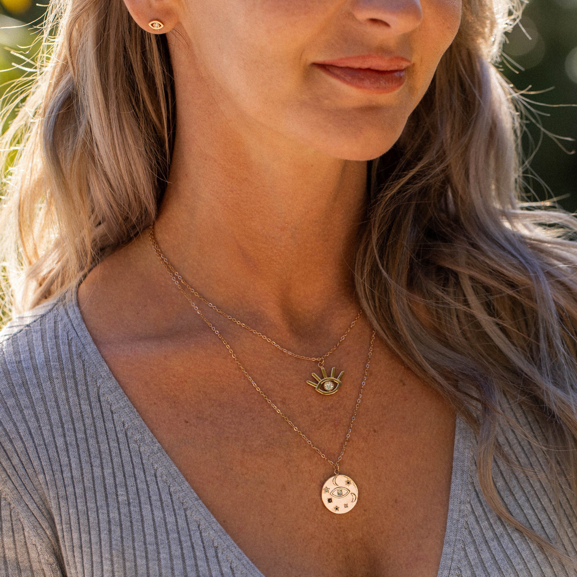 Zwei goldene Ketten mit Anhängern, getragen von einer Frau, PURELEI inspiriert.