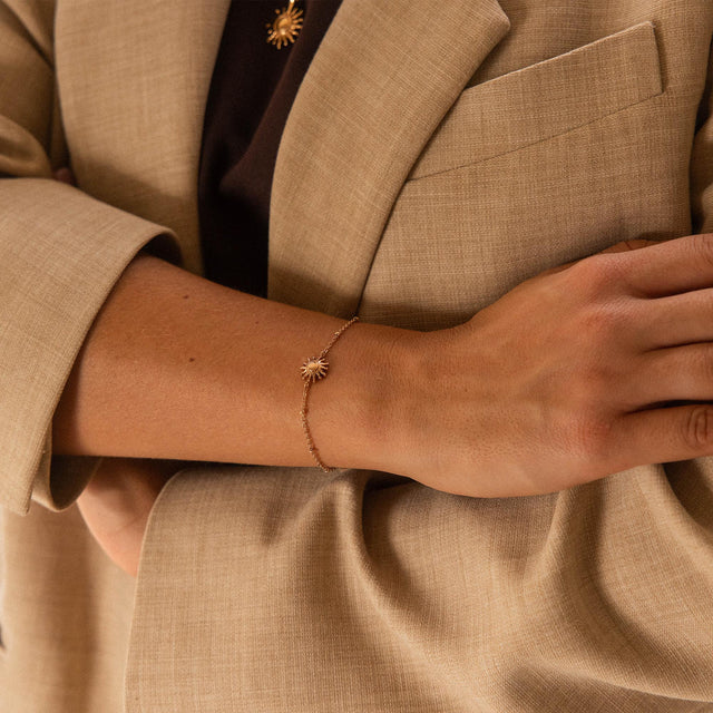 Goldenes Armband mit Sonnenmotiv, getragen am Handgelenk, von PURELEI.