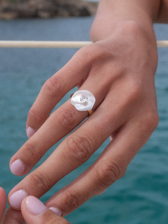 PURELEI Allure Ring mit Muschelperle und Zirkonia, 14K goldvergoldet, getragen vor Meereshintergrund, elegant feminin