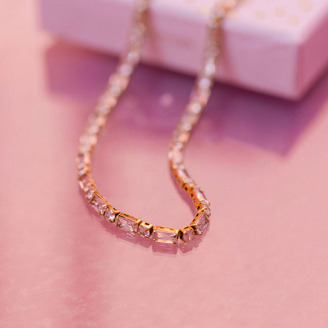 Roségoldene Kette mit funkelnden Steinen, elegant auf sanftem Untergrund, PURELEI.