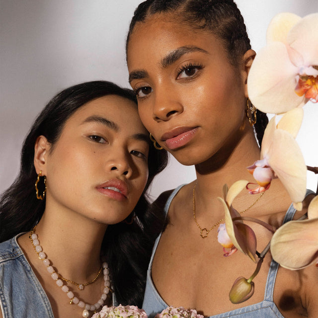 PURELEI Bloom Ohrringe in goldener Blütenform, getragen bei natürlichem Licht, elegant und feminin inszeniert