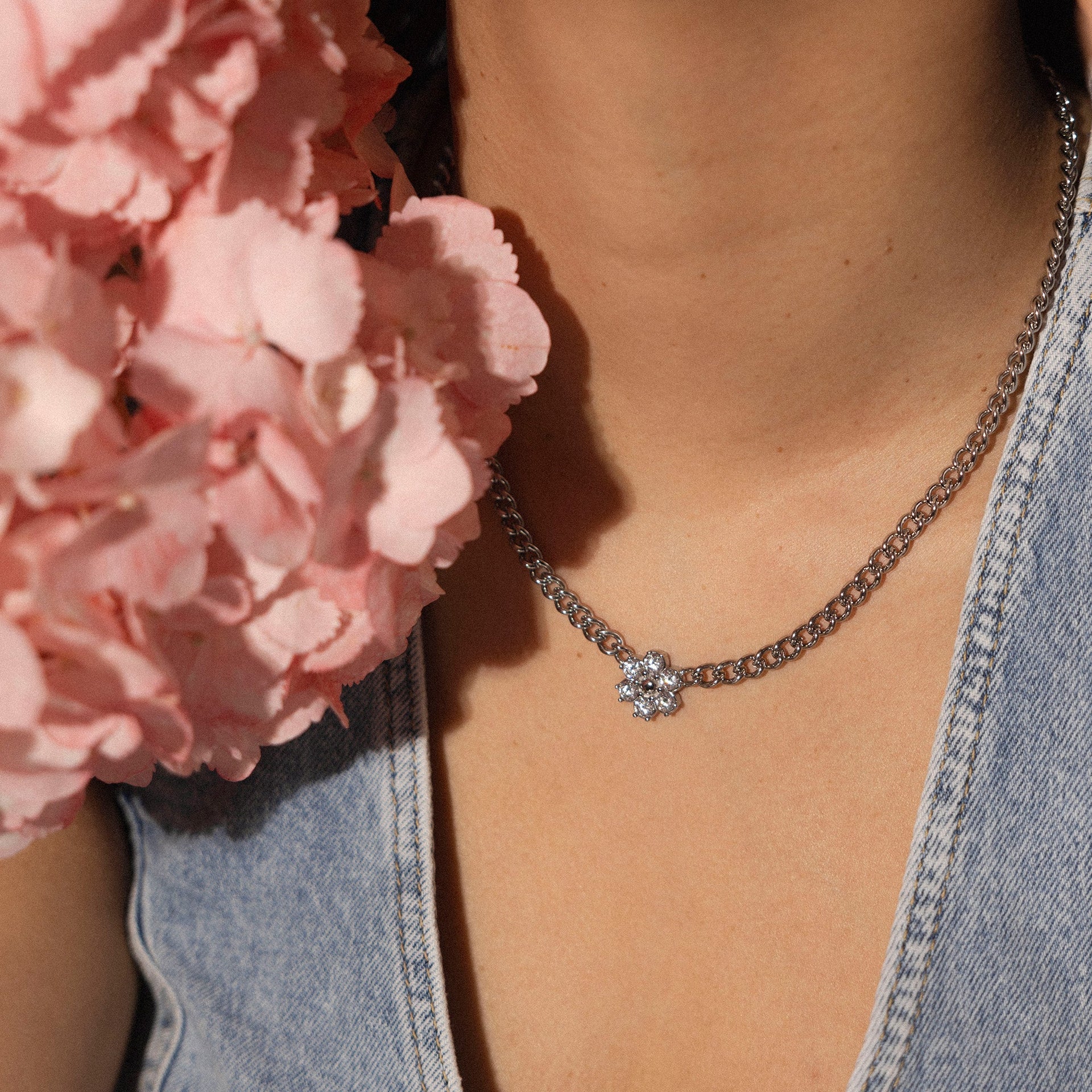Silberne Kette mit blütenförmigem Anhänger, getragen mit floralen Akzenten – PURELEI.