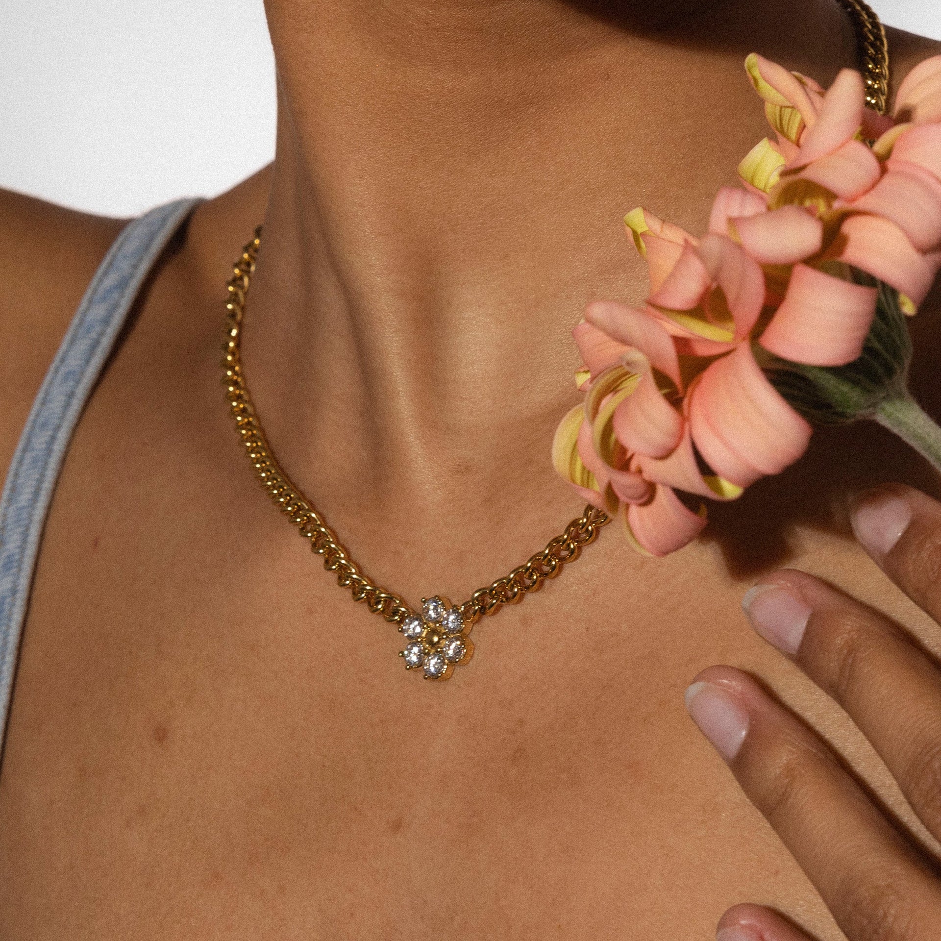 Roségoldene Kette mit blütenförmigem Anhänger, getragen mit zarten Blumen, von PURELEI.