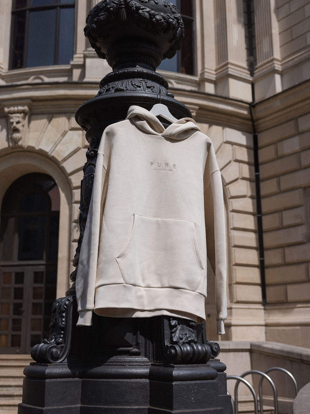 Feeling Pure Hoodie Beige aus Baumwolle mit Stickerei, oversized und lässig an historischem Gebäudepfeiler, PURELEI.