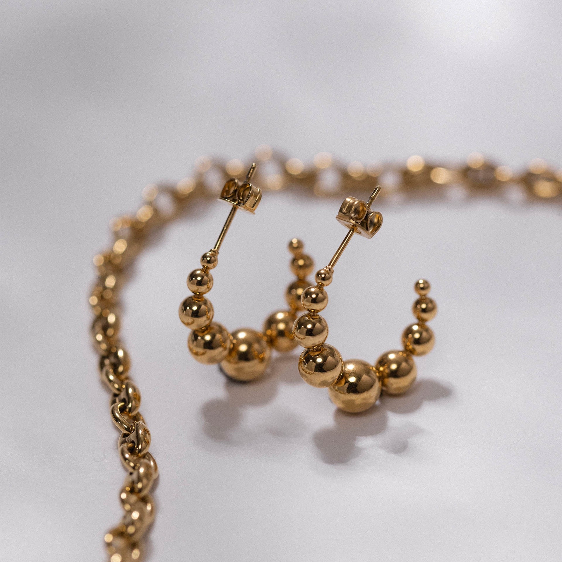 Goldene Creolen mit Kugeldesign von PURELEI, elegant und modern.