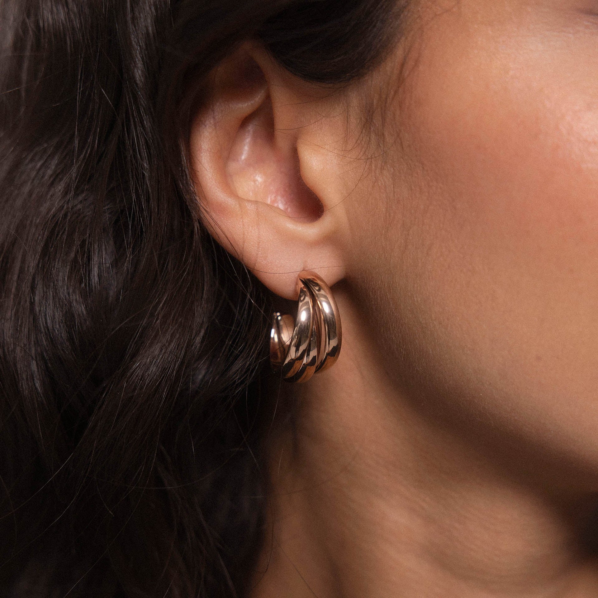 Roségoldene Creolen mit geschwungenem Design, getragen am Ohr, von PURELEI.