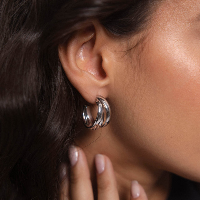 Roségoldene Creolen mit geschwungenem Design, getragen am Ohr, von PURELEI.