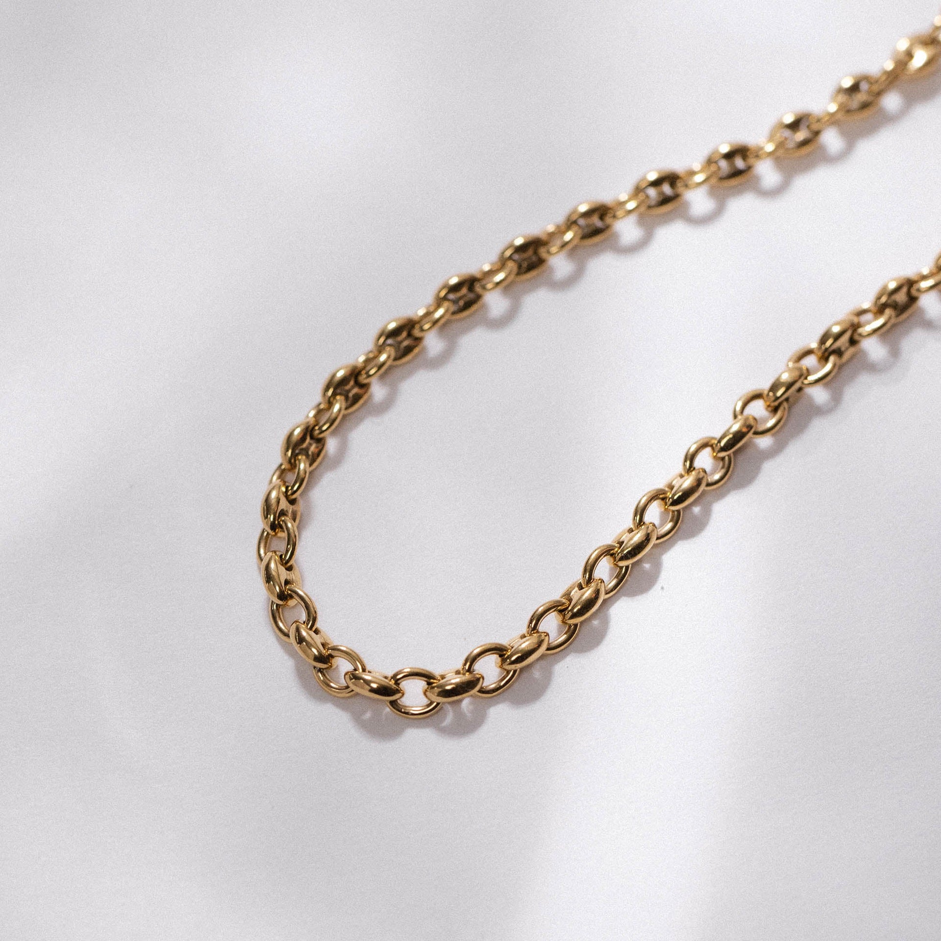 Goldene Kette mit ovalen Gliedern auf hellem Hintergrund, PURELEI inspiriert.