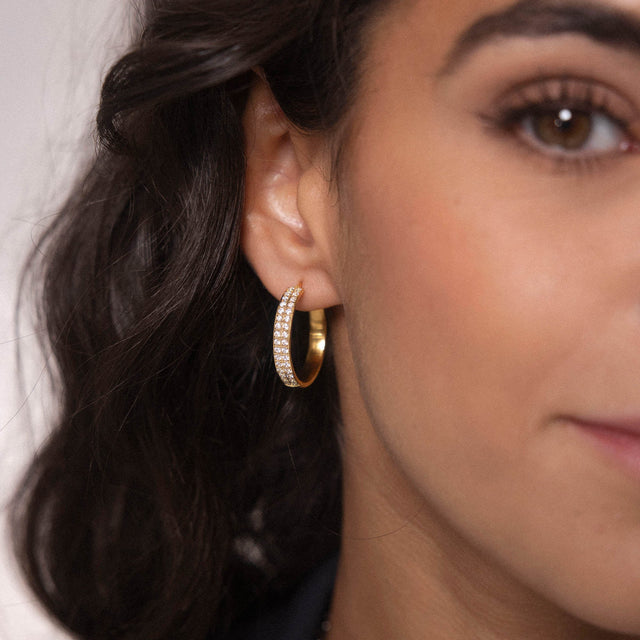 Roségoldene Creolen mit funkelnden Steinen, getragen von PURELEI.