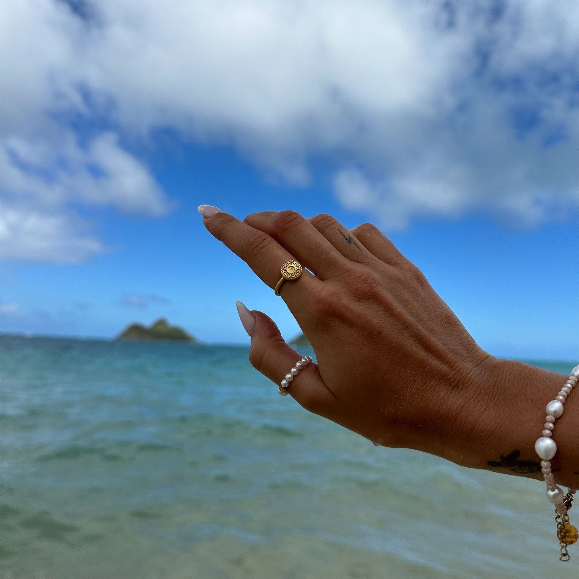 Waina Ring aus vergoldetem Edelstahl mit filigranem Coin, getragen am Strand – PURELEI, elegant und femininer Schmuck.