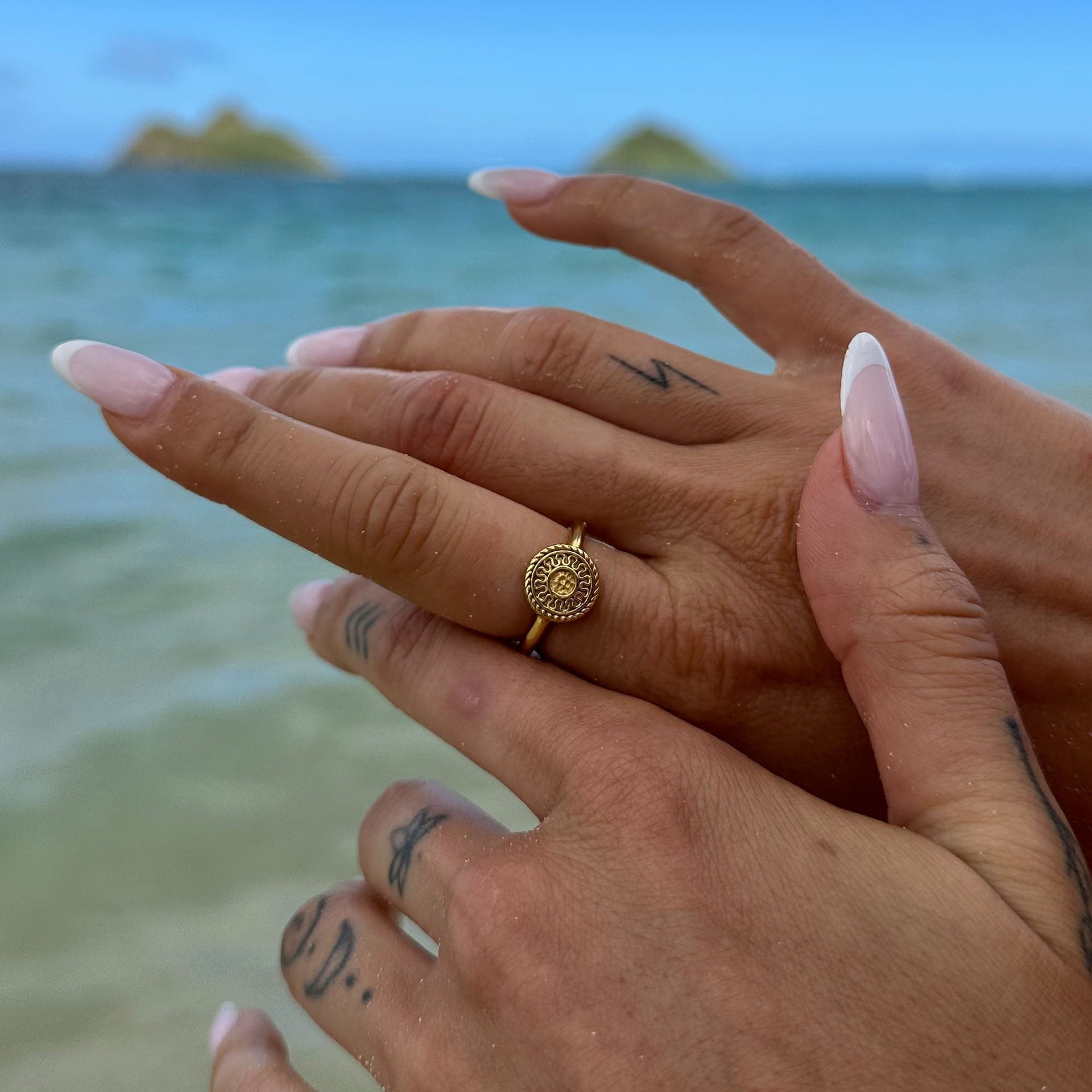 Waina Ring in Gold von PURELEI mit filigran geprägtem Coin, getragen am Strand, elegant und zeitlos.