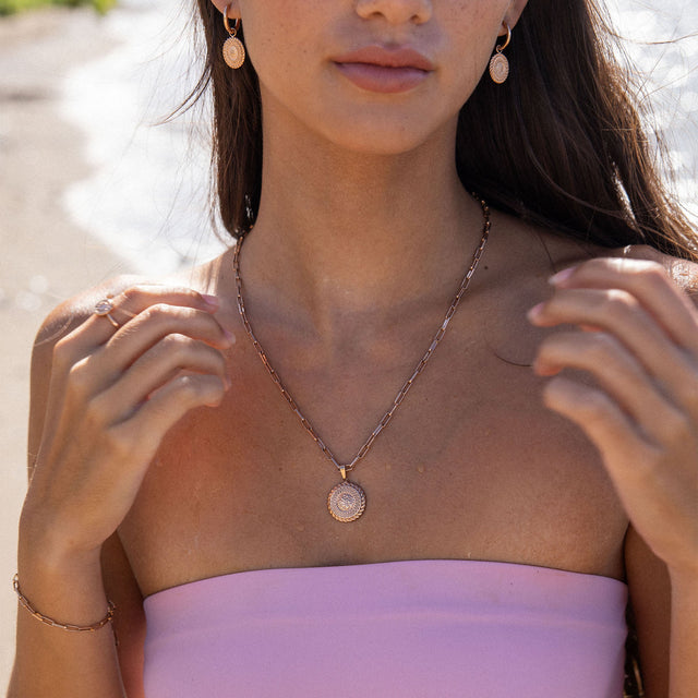 PURELEI Waina Kette Roségold mit filigranem Charm, getragen am Strand in warmem Sonnenlicht, elegant und feminin