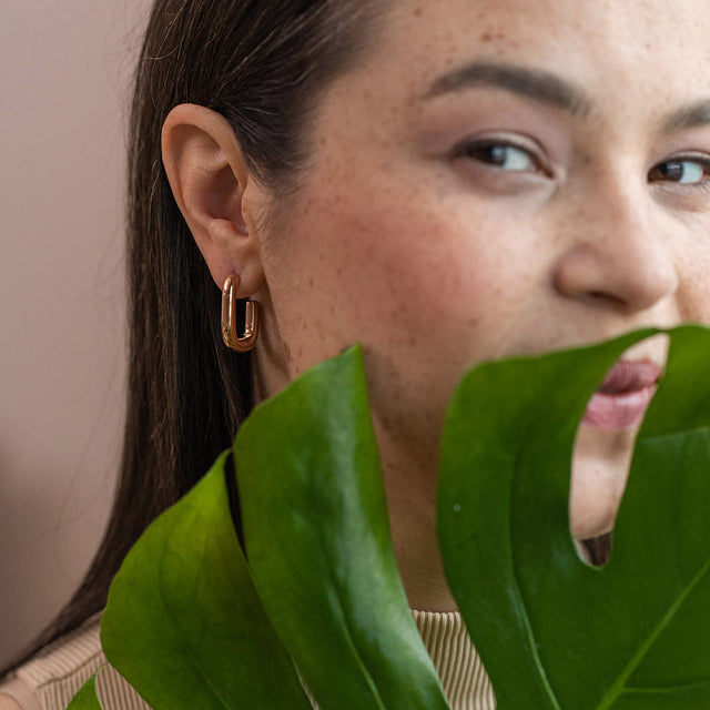 PURELEI Hula Ohrringe in Roségold, cleanes Design, getragen vor tropischem Blatt für elegante Island-Vibes.
