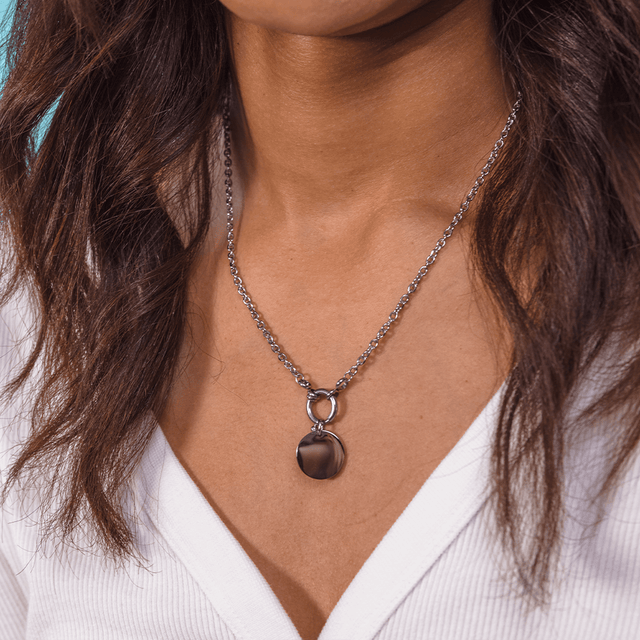 PURELEI Plate Charm in silberfarbenem Edelstahl, minimalistisch elegant, getragen zu weißem Shirt, zeitlos modern.