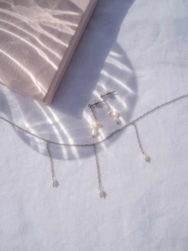 Silbernes PURELEI Mahina Club Purely Set mit natürlichen Süßwasserperlen auf weißem Leinentuch, elegant und zeitlos