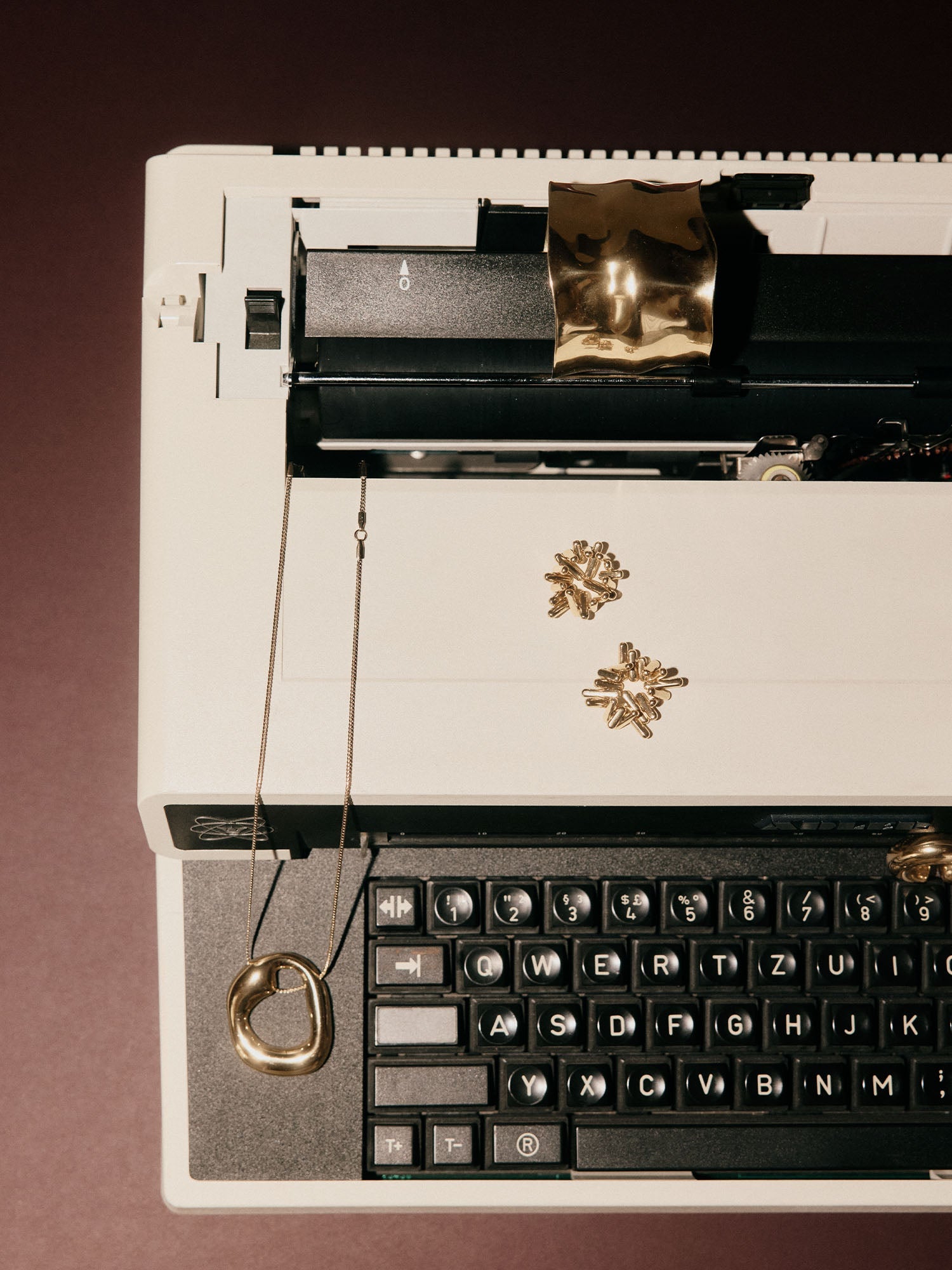 Silberne Kette mit organischem Anhänger auf einer Schreibmaschine, PURELEI inspiriert.
