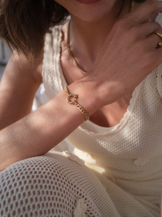 PURELEI Bold Charm Armband aus goldfarbenem Edelstahl mit Charm-Verschluss, elegant am Handgelenk getragen.