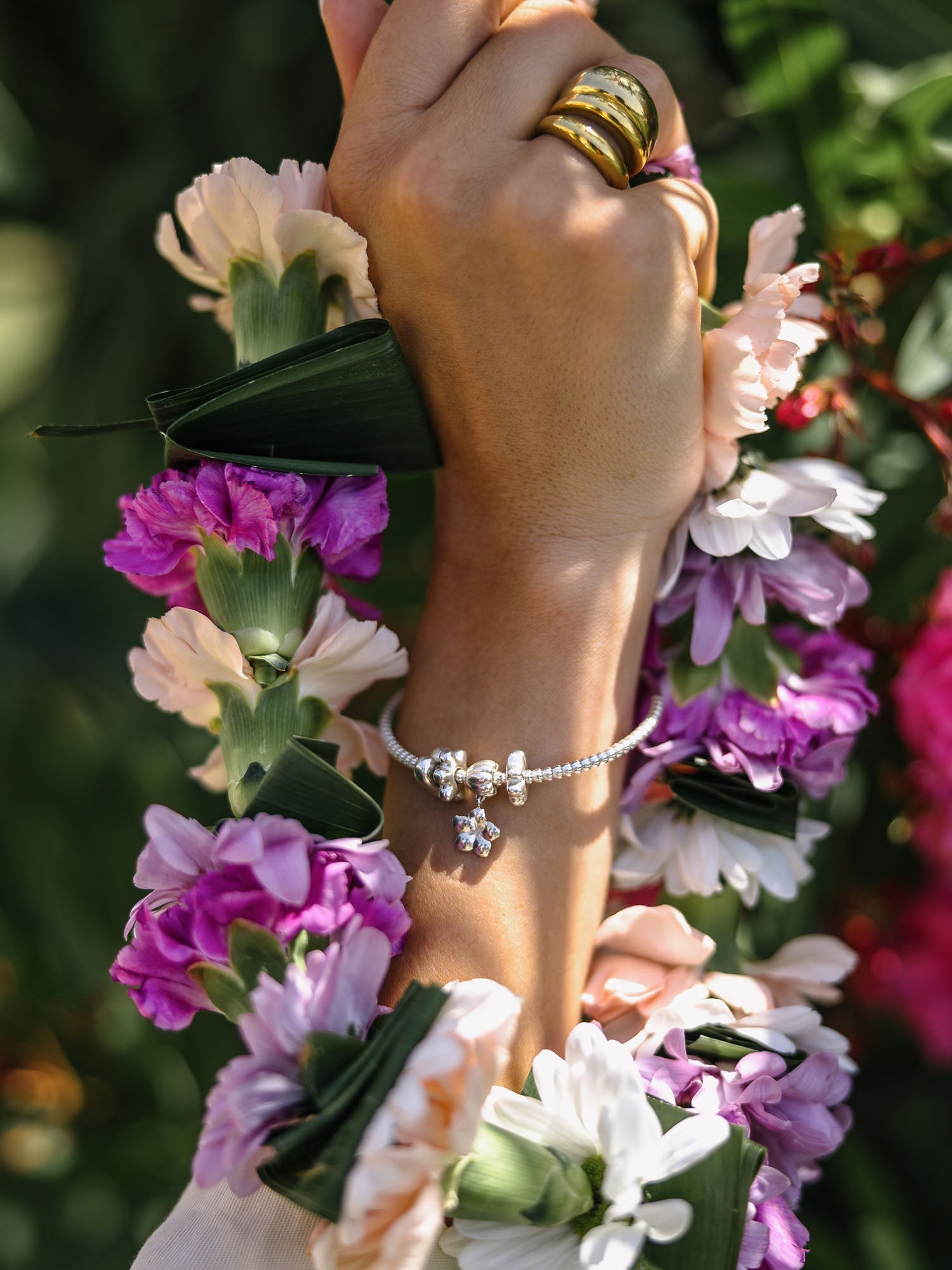 PURELEI Lei Orchidee Charm Armband aus Silber mit filigranem Orchideen-Anhänger in tropischer Blütenkulisse
