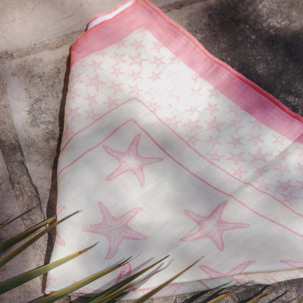 Zarte, rosa-weiße Tuch mit Sternenmotiv von PURELEI auf Steinuntergrund.