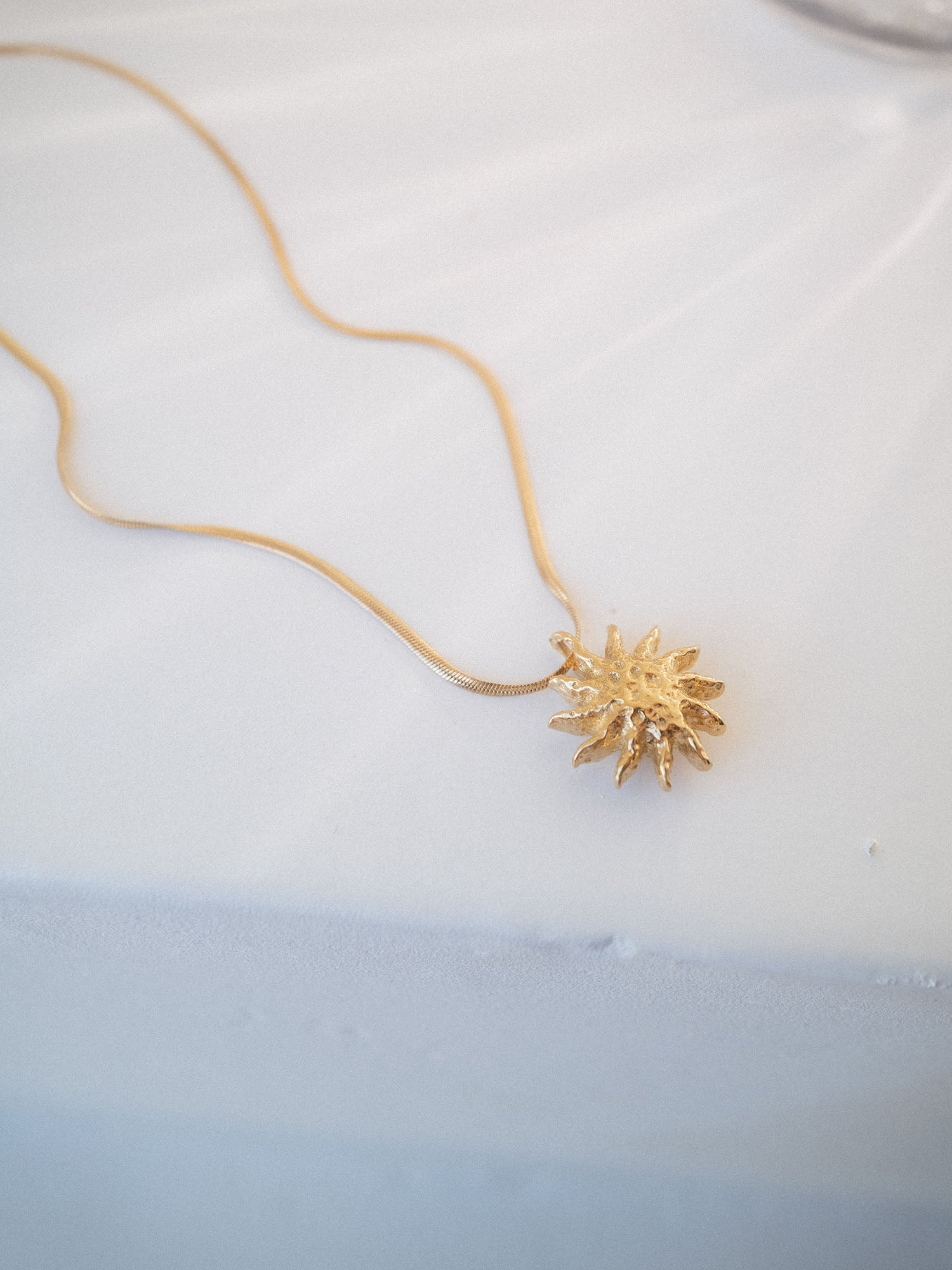 Filigrane PURELEI Iconic Sun Kette in 14K Gold mit strukturierter Sonnenanhänger auf hellem Hintergrund