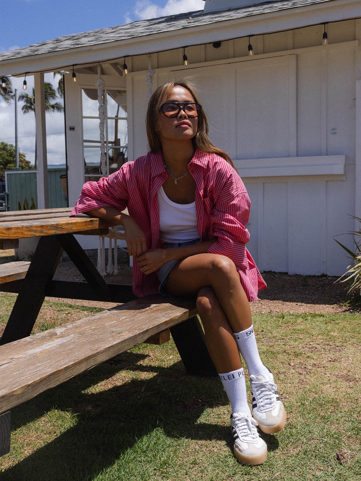 Frau in gestreifter Bluse und Sneakers, PURELEI Schmuck glänzt im Sonnenlicht.
