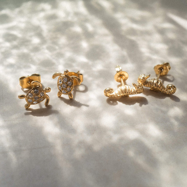 Goldene Ohrringe in Schildkröten- und Muschel-Design von PURELEI, funkelnd und verspielt.