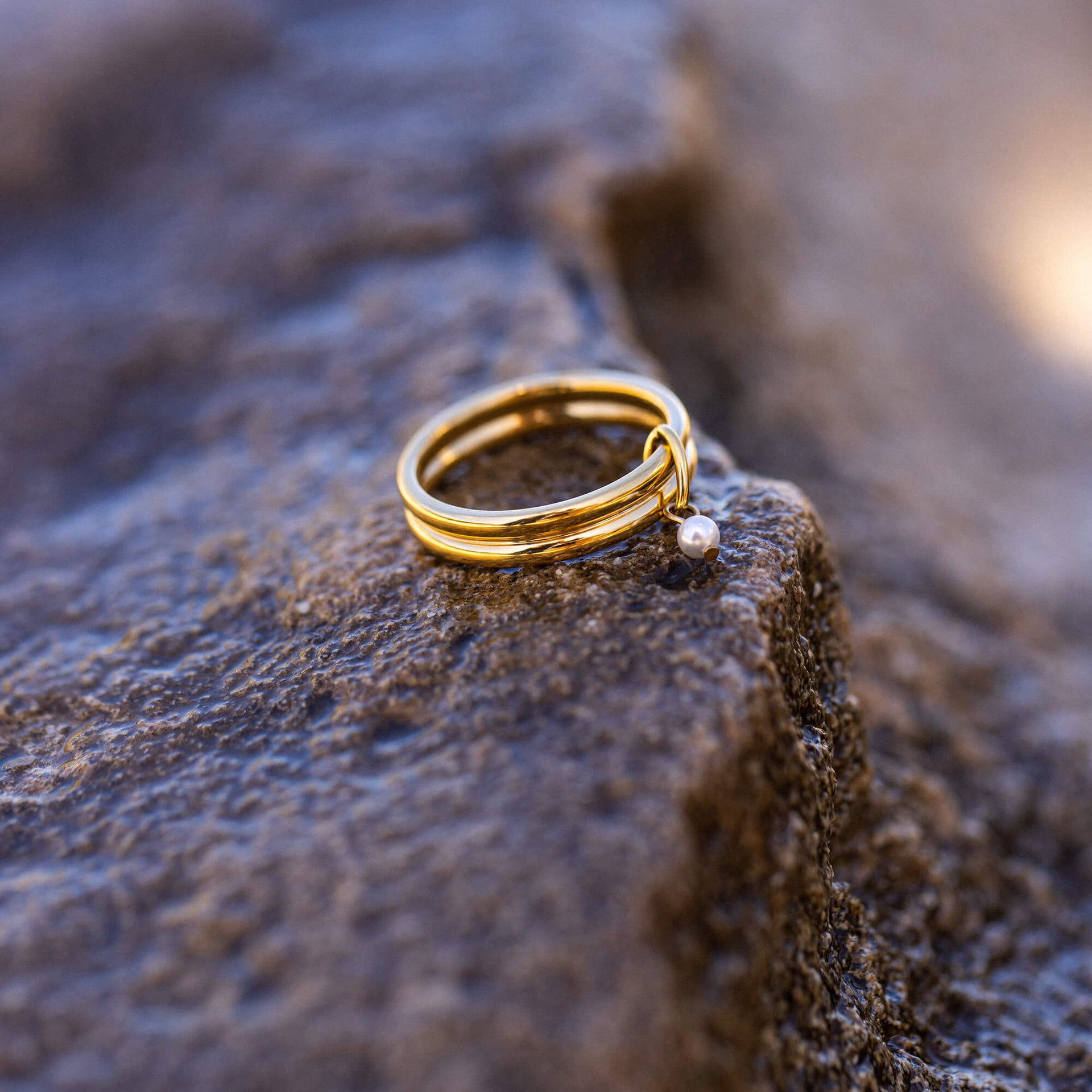 Doppelreihiger Perlenring aus 18K Gold Edelstahl mit Muschelperle auf rauem Stein, PURELEI zeitlos elegant.