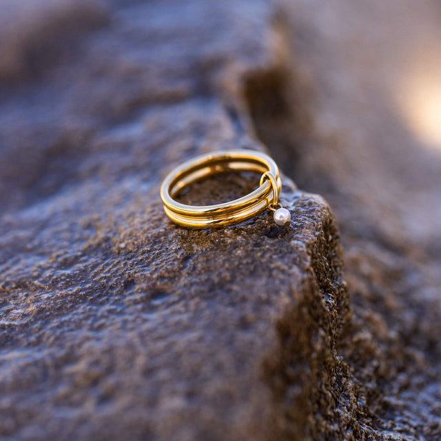 Doppelreihiger Perlenring aus 18K Gold Edelstahl mit Muschelperle auf rauem Stein, PURELEI zeitlos elegant.