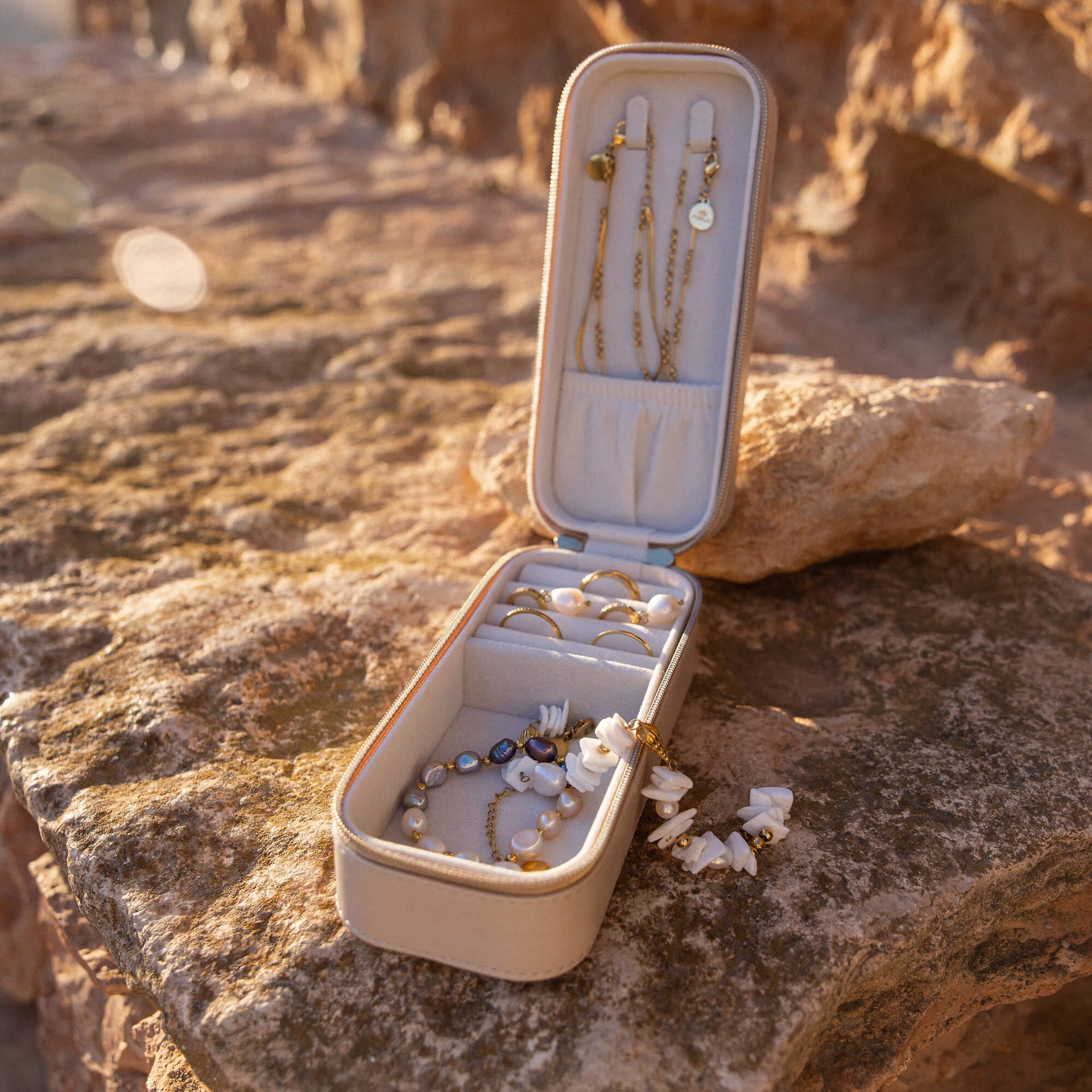 Elegante Schmuckbox mit goldenen und weißen Schmuckstücken von PURELEI, umgeben von natürlichem Licht.