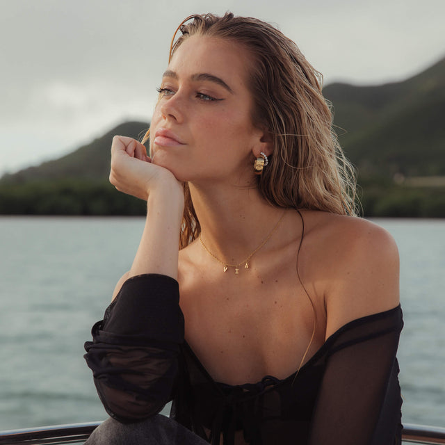 PURELEI Pure Soul Ohrringe aus goldfarbenem Edelstahl mit perlenbesetzten Creolen, elegant und feminin am Wasser.