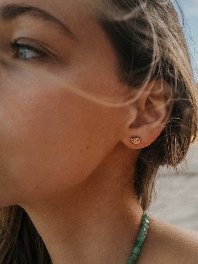 Silberne Ohrstecker mit spiralförmigem Design, getragen von einer Frau, PURELEI.
