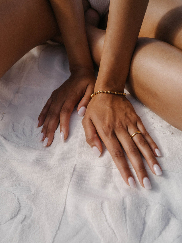 Roségoldenes Armband und feiner Ring auf zarten Händen, umgeben von weichem, weißen Tuch – PURELEI.