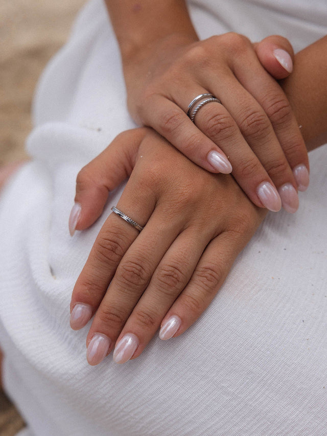 Silberne Ringe von PURELEI, elegant gestapelt auf zarten Händen mit glänzendem Nagellack.
