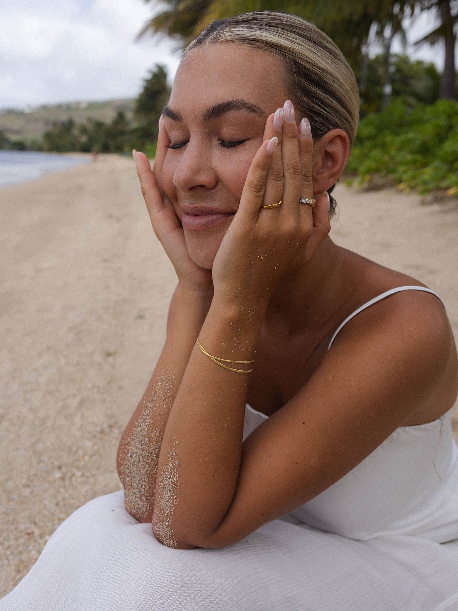 Frau am Strand mit PURELEI Armband, entspannte Stimmung, zarte Eleganz in Weiß.
