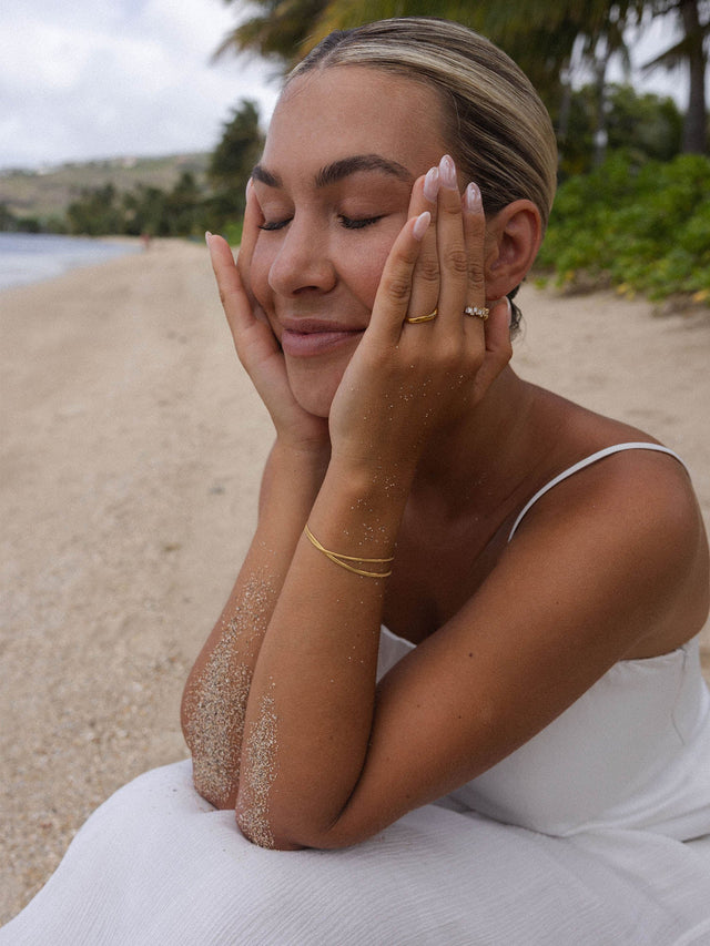 Frau am Strand mit PURELEI Armband, entspannte Stimmung, zarte Eleganz in Weiß.