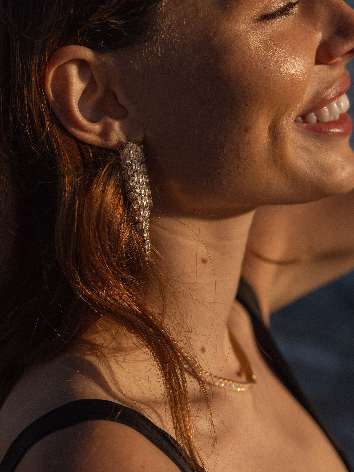 Elegante, goldene Ohrringe mit strukturiertem Design, getragen von einer lächelnden Frau, PURELEI.