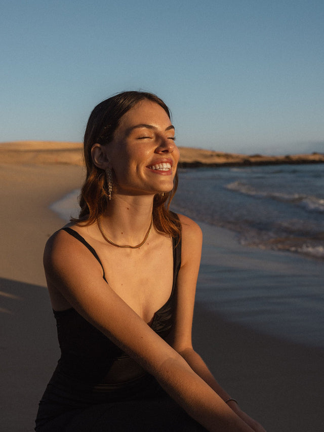 PURELEI Schmuck, elegant und feminin, am Strand in warmem Licht getragen.