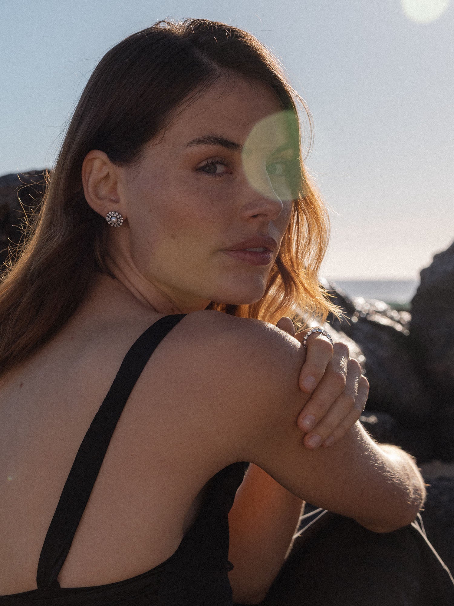 Elegante, silberne Ohrringe mit floralem Design, getragen von einer Frau am Strand – PURELEI.