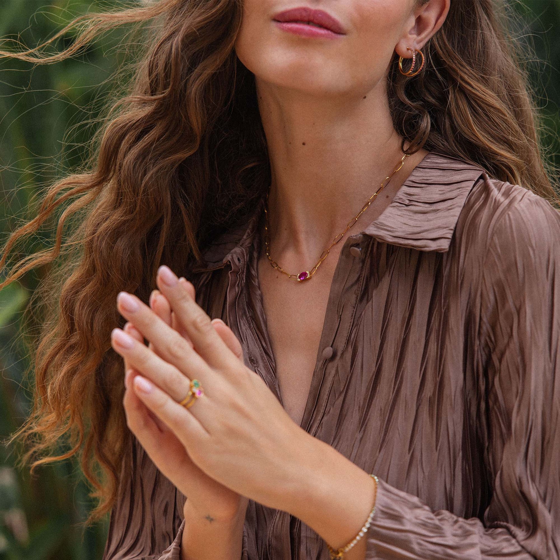 Goldene Kette und Creolen von PURELEI, elegant und feminin, umgeben von tropischer Natur.