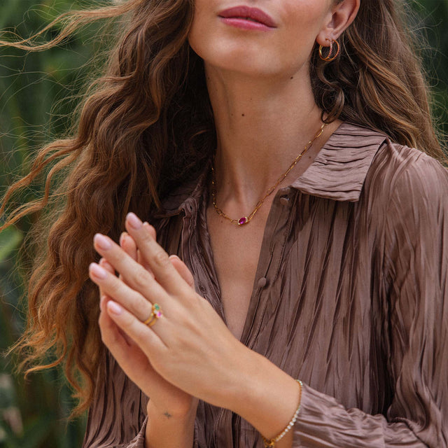 Goldene Kette und Creolen von PURELEI, elegant und feminin, umgeben von tropischer Natur.